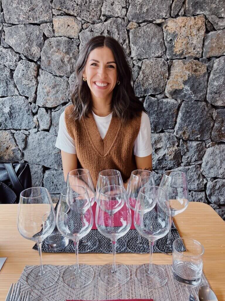 Linds Alyse sitting in front of wine glasses at a wine tasting in Sicily 