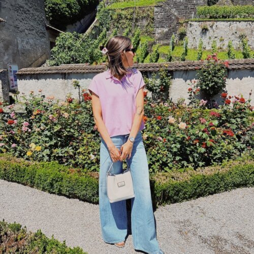 Linds Alyse wearing jeans and a pink shirt in a rose garden