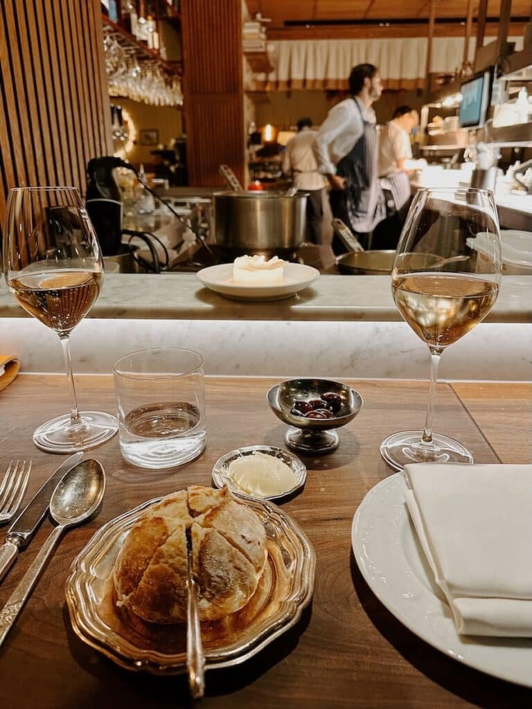 A table filled with fresh bread and butter, olives, and wine at an Amsterdam restaurant recommendation 

