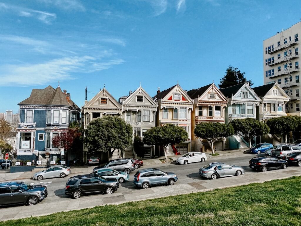 The iconic Painted Ladies of San Francisco, a row of colorful Victorian houses with the city skyline in the background, seen from Alamo Square Park.