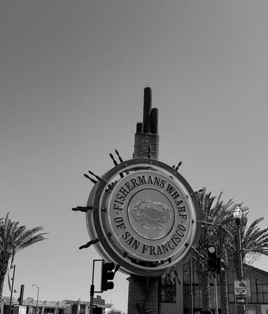 A lively view of Fisherman’s Wharf, with bustling crowds, seafood stalls, and a waterfront backdrop filled with boats.