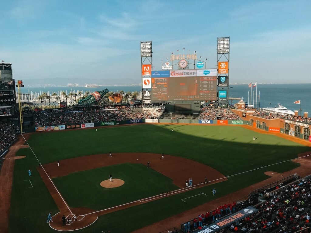 Wide view of Oracle Park stadium in San Francisco, with a vibrant baseball field and fans filling the stands during a daytime Giants game.