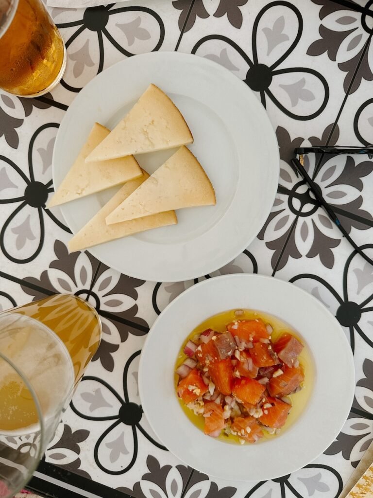 Enjoying traditional Spanish tapas with cheese, fresh salmon ceviche, and a cold beer—one of the tastiest things to do in Seville.