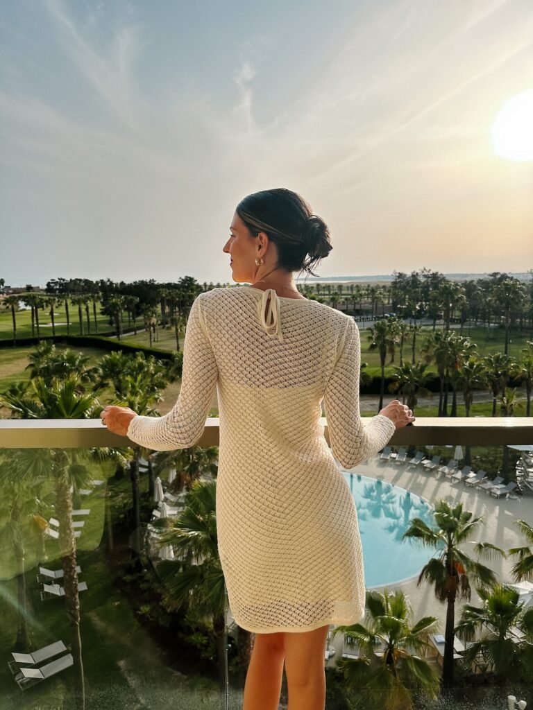 a crochet dress worn by a women with a slick backed bun during sunset is one of the perfect women’s travel dresses
